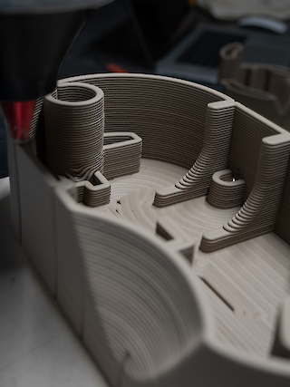 Clay is printed on a custom generated path, finding its way around the standard components in a single continuous line.